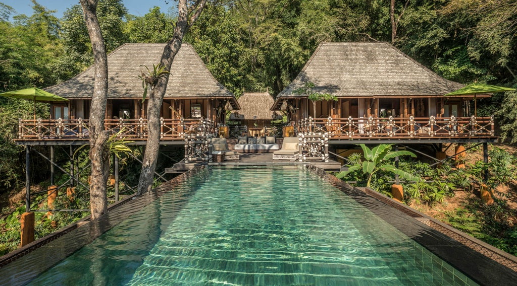 Luxurious tented lodge room with teak furnishings, canopy bed, jungle views, natural materials and rustic-chic decor in Thai style