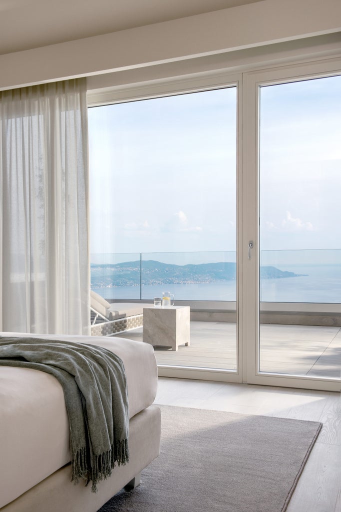 Elegant Sky Suite with floor-to-ceiling windows, private terrace, designer furnishings, and panoramic views over Lake Garda at sunset