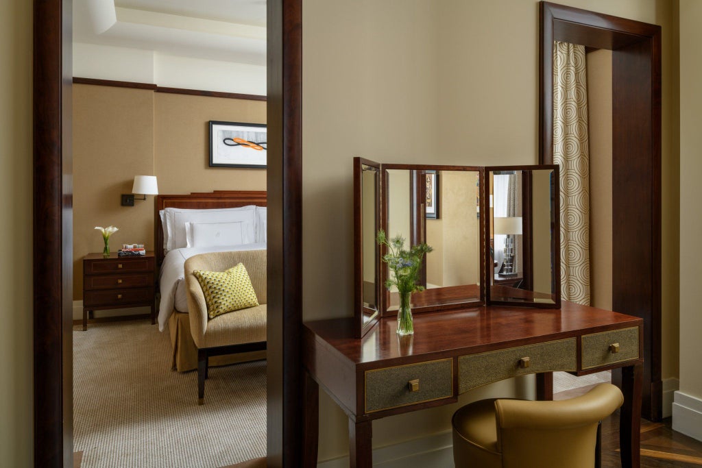 Elegant Mayfair suite with plush cream-colored furnishings, rich wood accents, designer lighting, and expansive city view through large windows