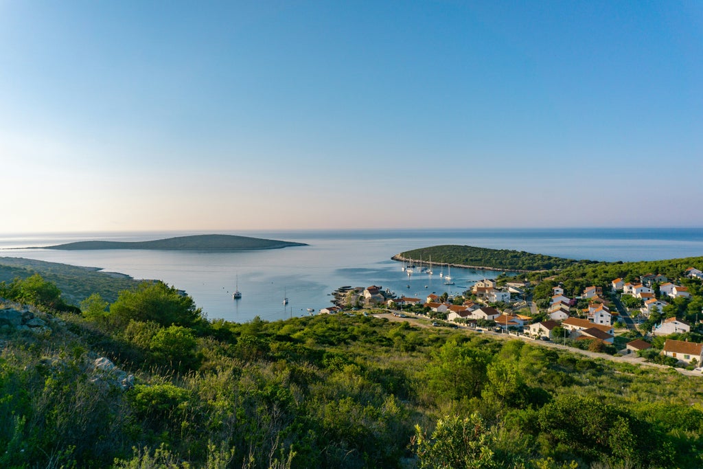 Sleek private yacht glides past Croatia's scenic coastline, featuring crystal-clear turquoise waters and rugged limestone cliffs at sunset