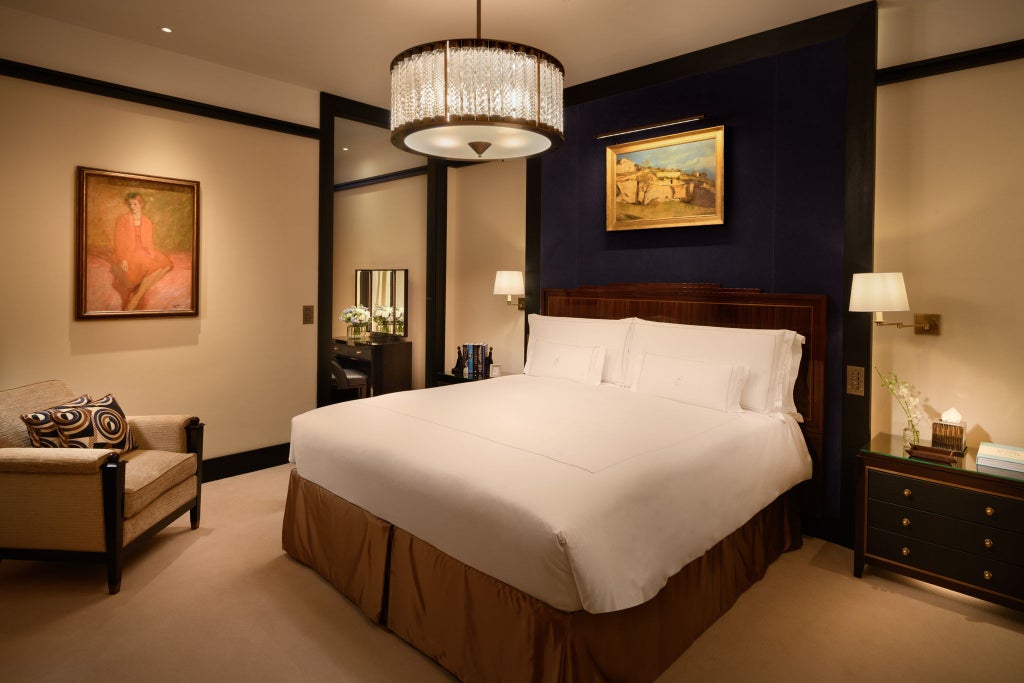 Luxurious Mayfair suite with elegant cream and gold decor, plush king bed, designer furniture, and sophisticated city view through large windows