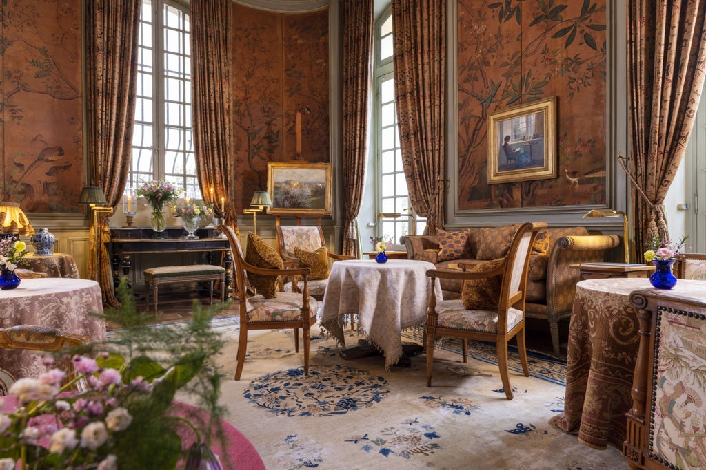 Interior of La Mirande hotel's dining room with elegant crystal chandeliers, antique wall tapestries, and ornate place settings on white tablecloths