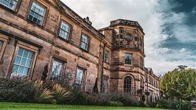 Luxurious three-story historic manor hotel with Georgian architecture, manicured gardens, and elegant stone facade in scenic United Kingdom countryside