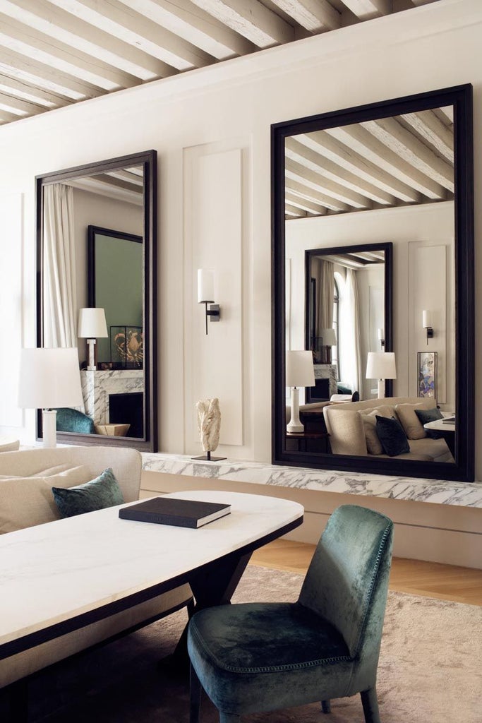 Elegant Venetian-style suite with ornate chandeliers, antique furnishings, plush velvet chairs, and panoramic windows overlooking historic Castello district in Venice