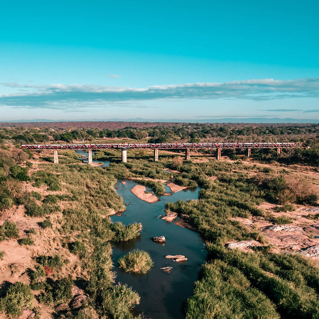 Historic train transformed into luxury hotel rooms perched on Kruger bridge, offering panoramic views of African wilderness below