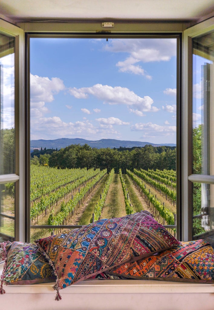 Elegant Tuscan luxury hotel nestled among rolling hills, featuring stone architecture, manicured gardens and cypress-lined driveway