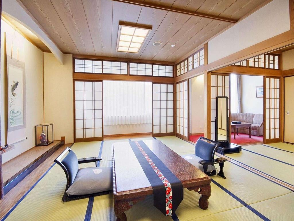 Traditional Japanese ryokan with wooden facade, featuring illuminated paper lanterns and elegant entrance walkway lined with bamboo plants