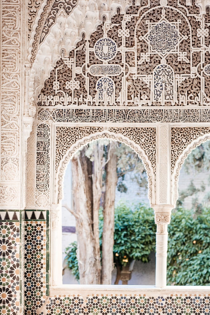 Ornate Moorish architecture of Alhambra's palace with intricate carved arches, sunlight casting golden shadows on marble courtyards and elegant Islamic geometric patterns