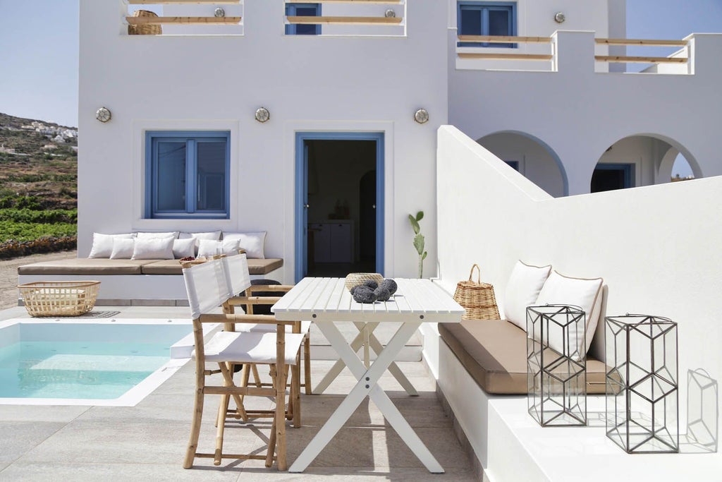 Luxurious whitewashed Greek villa with blue-domed roof, nestled on Santorini's cliffside, overlooking azure Aegean Sea with elegant stone terrace and traditional architecture