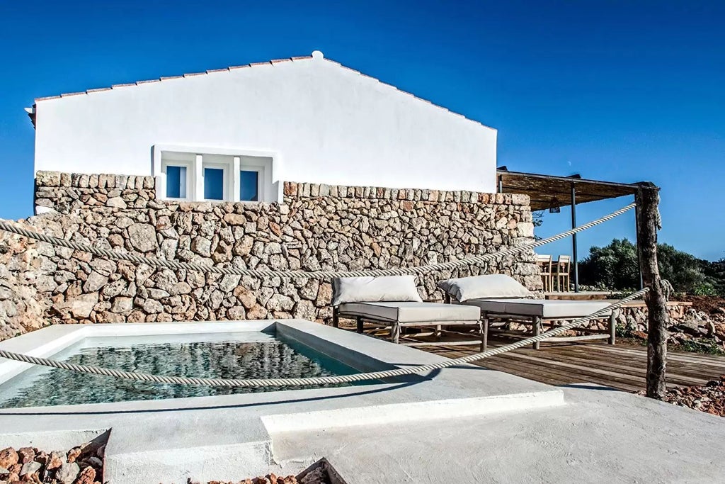 Luxurious white and blue pool suite at scenic Spanish coastal resort, featuring elegant minimalist design and panoramic Mediterranean views