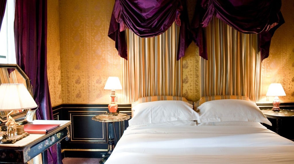 Elegant French luxury hotel room with plush white bedding, ornate crystal chandelier, and soft neutral tones reflecting Parisian boutique design aesthetic