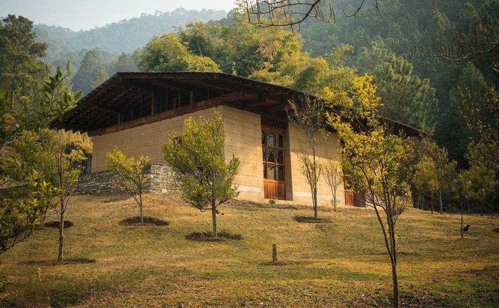 Traditional Bhutanese lodge with infinity pool overlooking misty mountain valley, stone terrace and rustic wood architecture