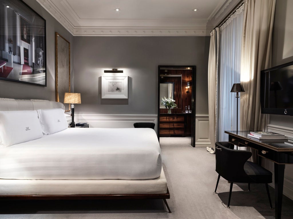 Elegant grand deluxe hotel room with neutral tones, plush white bedding, marble details, and sophisticated Italian design overlooking Rome's historic landscape