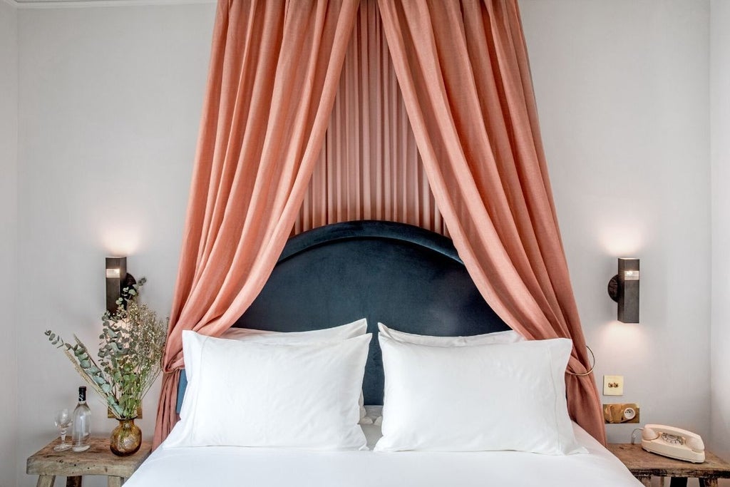 Luxurious French hotel room with elegant white and gold decor, plush king-sized bed, ornate chandelier, and large windows overlooking Paris boulevard