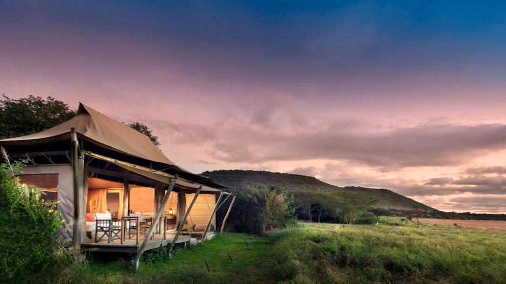 Luxurious safari tent overlooking the Masai Mara savanna, with private wooden deck, elegant furnishings and sweeping grassland views