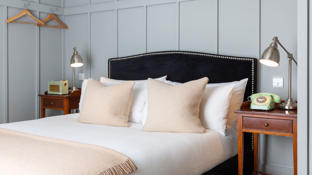 Elegant boutique hotel room with plush bedding, modern bathroom featuring bath and shower, soft neutral tones in a luxurious United Kingdom accommodation