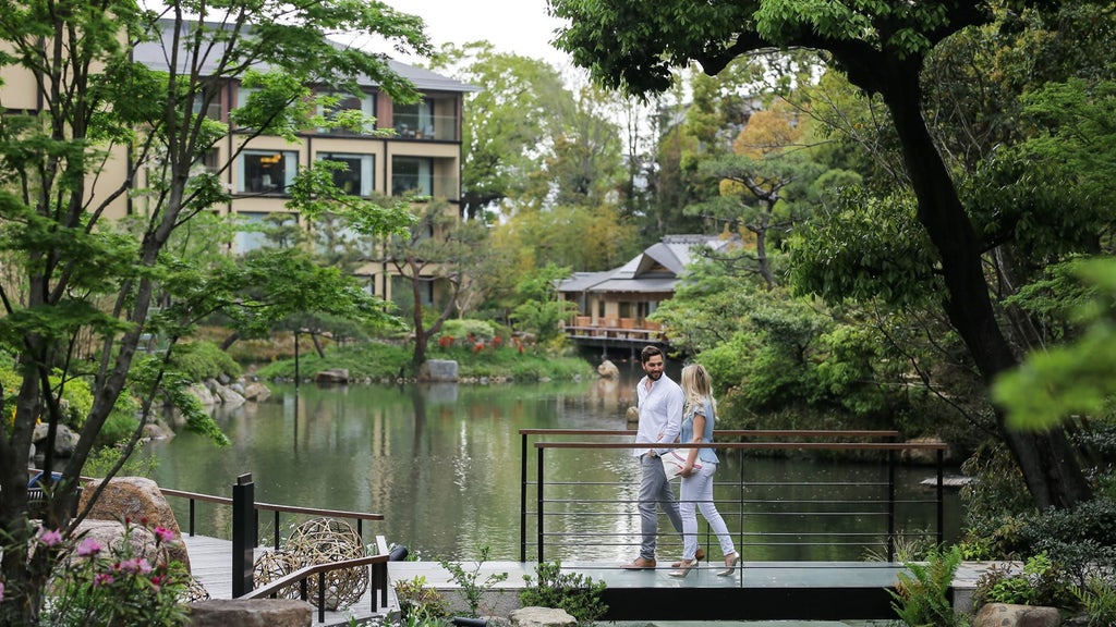 Elegant Japanese garden pond with wooden bridge, surrounded by manicured trees and reflecting traditional architecture of Four Seasons Kyoto