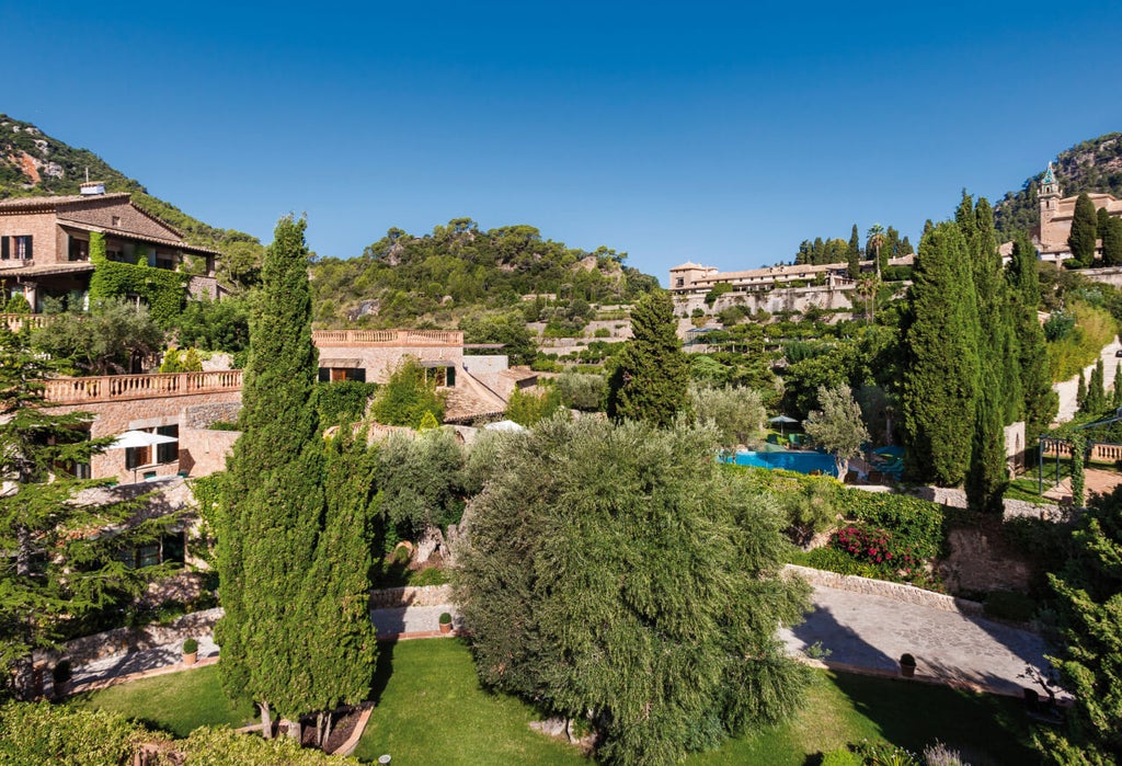 Elegant stone hotel nestled in Mallorca's mountains, featuring terracotta roof tiles, manicured gardens and panoramic valley views