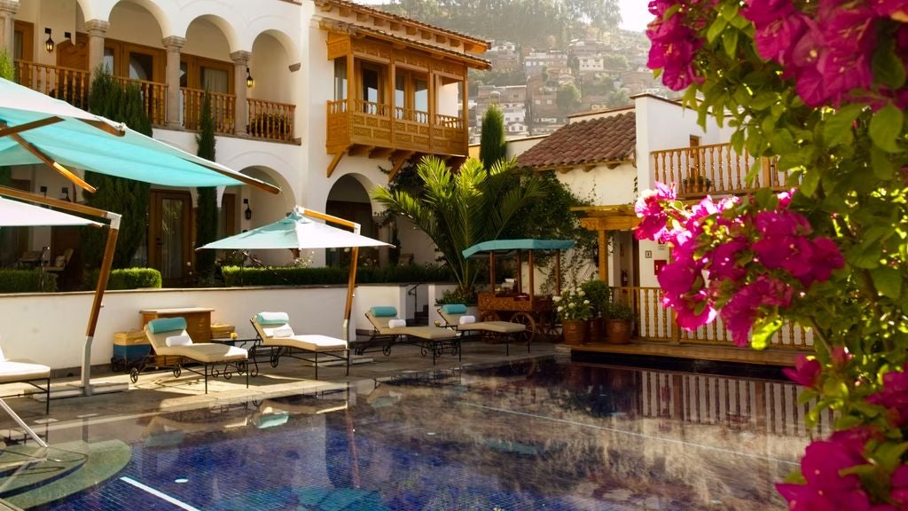 Historic luxury hotel with stone archways and colonial courtyard featuring manicured gardens and mountain views in Cusco, Peru