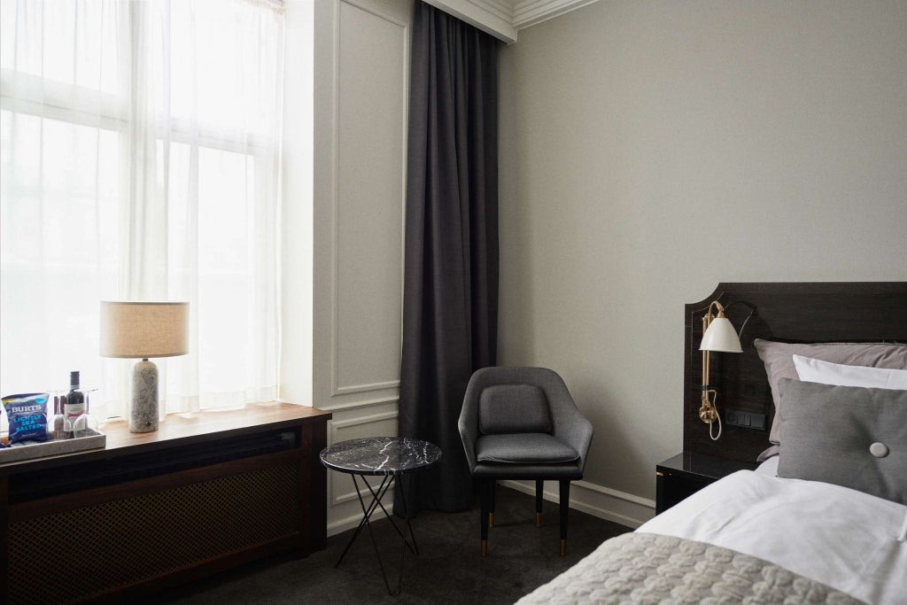 Elegant twin deluxe hotel room with modern furnishings, soft lighting, two plush beds, and minimalist Danish design featuring neutral tones and sleek decor