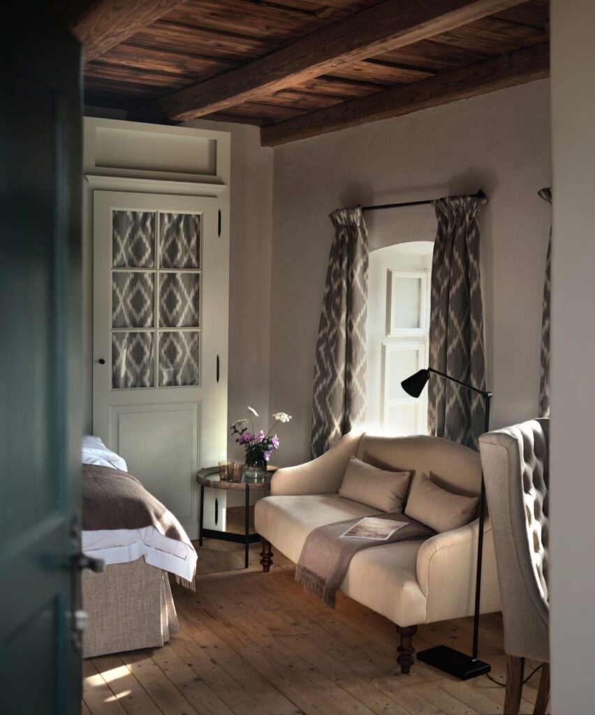 Rustic luxury bedroom in Transylvanian Depner House, featuring wooden beams, elegant four-poster bed, and traditional Romanian textiles in warm, inviting tones