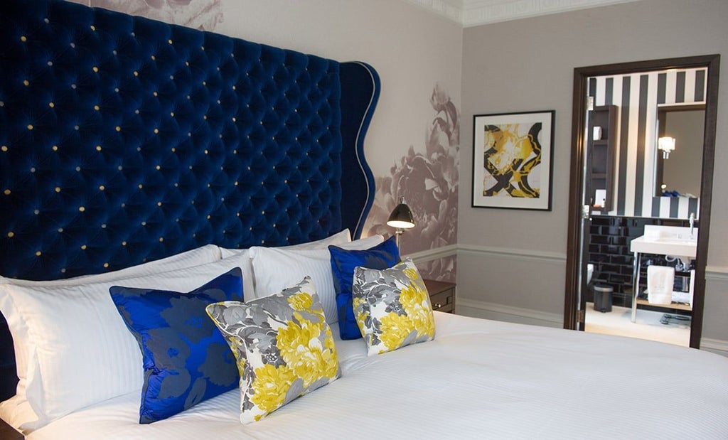 Elegant deluxe studio with contemporary design, featuring a plush king bed, modern artwork, soft neutral tones, and luxurious urban decor at a boutique UK hotel.