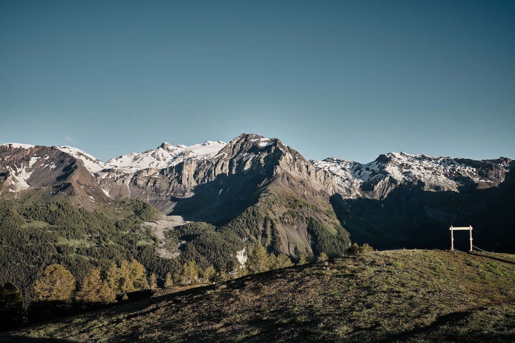 Luxurious alpine hotel room with panoramic mountain view, minimalist wood furnishings, floor-to-ceiling windows, and warm, natural Swiss mountain chalet aesthetic