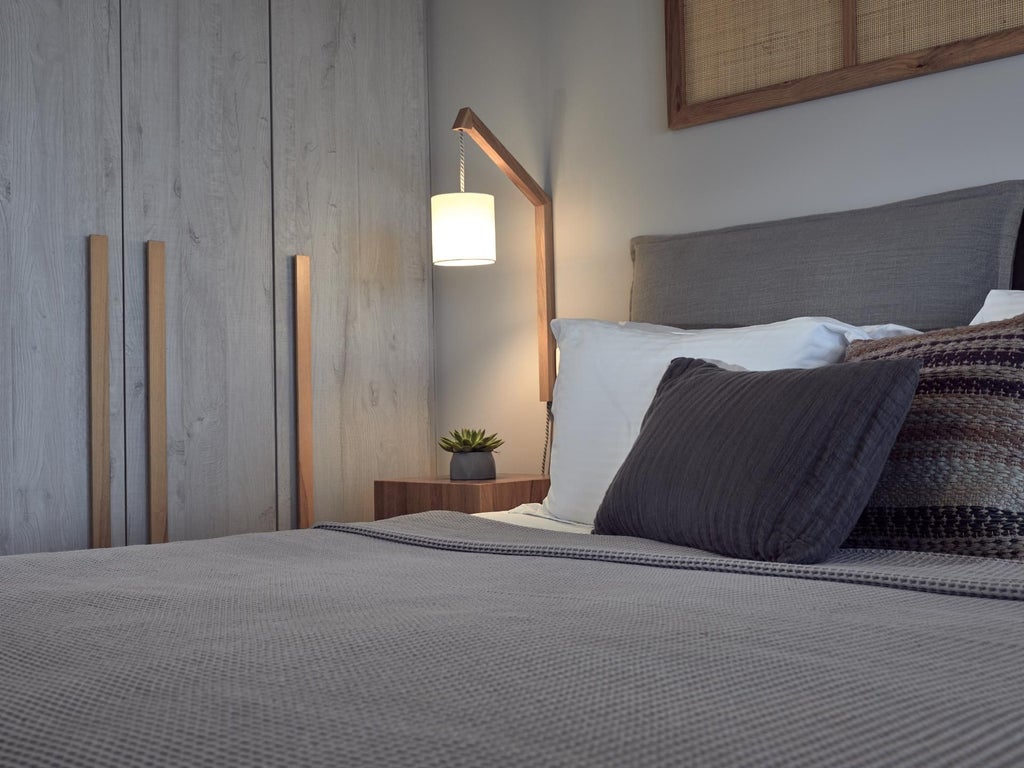 Luxurious white and blue Greek villa bedroom with panoramic sea view, elegant minimalist decor, and traditional Cycladic architectural elements overlooking azure waters