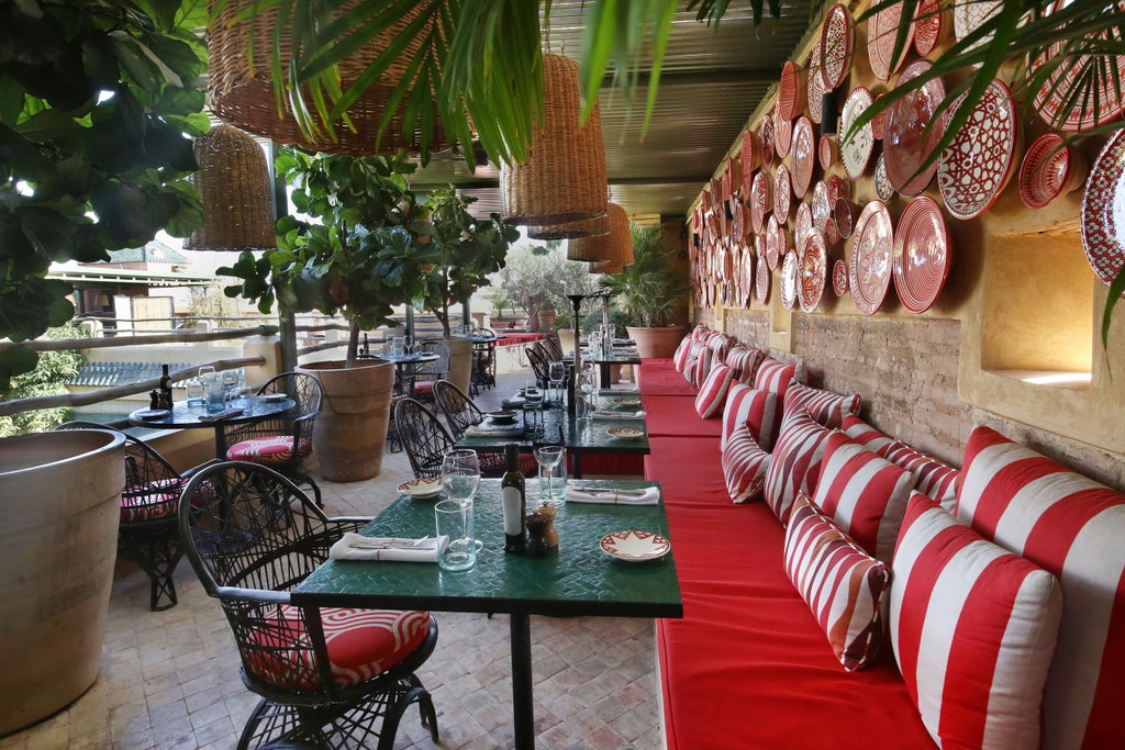 Opulent Moroccan riad with a rooftop pool overlooking Marrakech, featuring traditional tiles, archways and lush potted plants