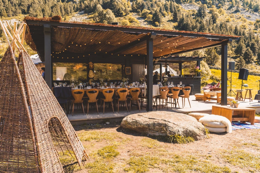 Rustic mountain lodge with warm wooden exterior, nestled in snow-capped Andorran peaks, showcasing cozy alpine luxury and inviting wilderness landscape