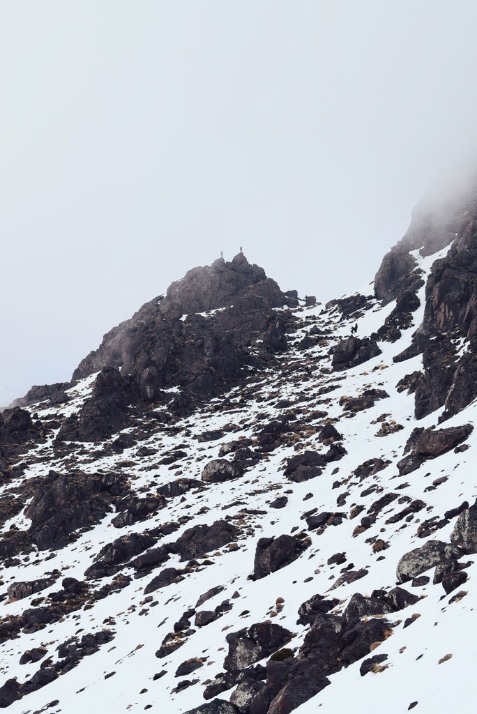 Rugged mountain terrain with Berber trekkers, leather hiking boots, traditional wool djellaba, panoramic Atlas Mountains landscape with distant snow-capped peaks