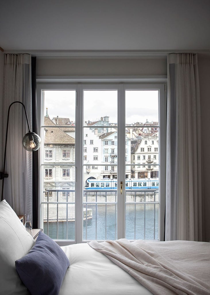 Historic Storchen Hotel in Zurich with elegant white facade, situated along Limmat River, featuring traditional Swiss architecture and balconies