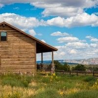 Rustic wooden lodge interior with warm earth tones, plush leather seating, panoramic mountain windows, and elegant southwestern decor at scenic destination accommodation