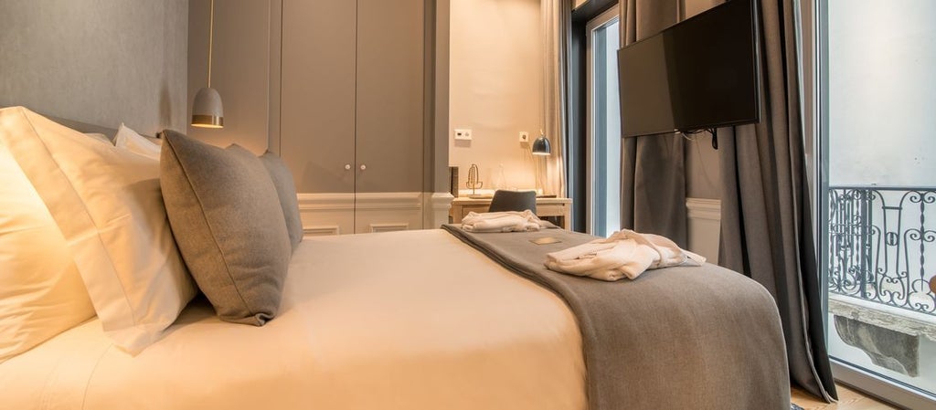 Luxurious hotel room at Hotel da Baixa with elegant decor, panoramic city views, modern furnishings, and expansive windows overlooking Scenset's urban landscape