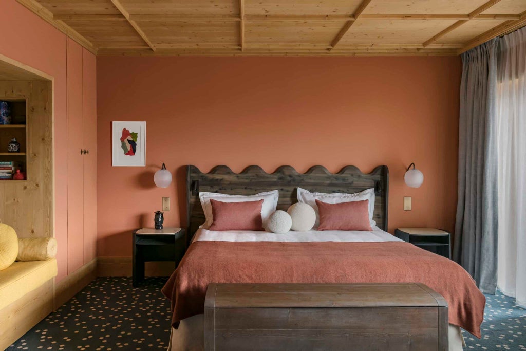 Elegant alpine-style Deluxe Junior Suite with warm wood paneling, plush white bedding, and expansive mountain views at Le Coucou luxury ski resort in Méribel