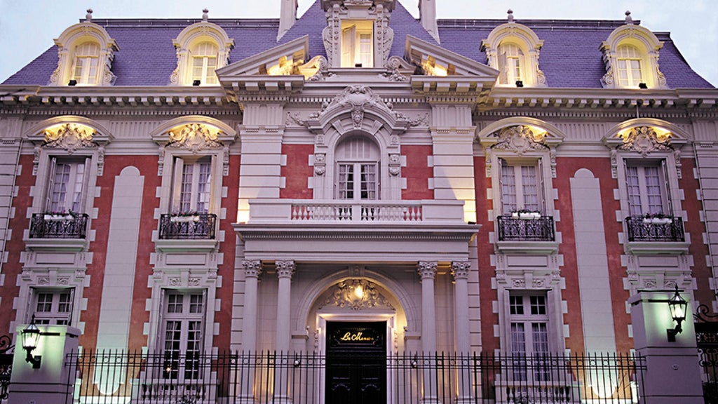 Elegant glass and stone facade of Four Seasons Buenos Aires hotel with French-inspired architecture, ornate balconies and manicured gardens