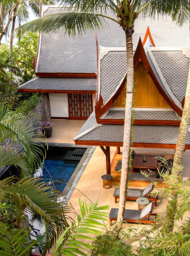 Elegant Thai pavilion bedroom with glass doors opening to private pool, lush gardens and teak furnishings in natural sunlight