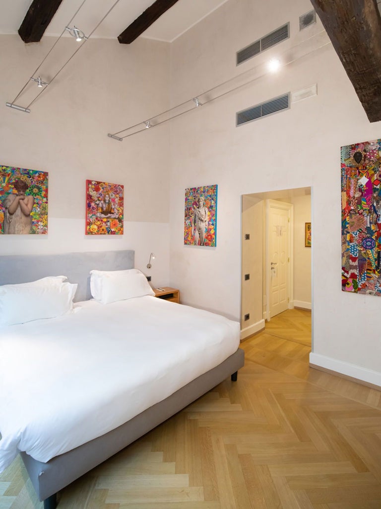 Elegant deluxe hotel room at Scenset Milano, featuring sleek modern design with bold art, luxurious white bedding, and sophisticated Italian aesthetic