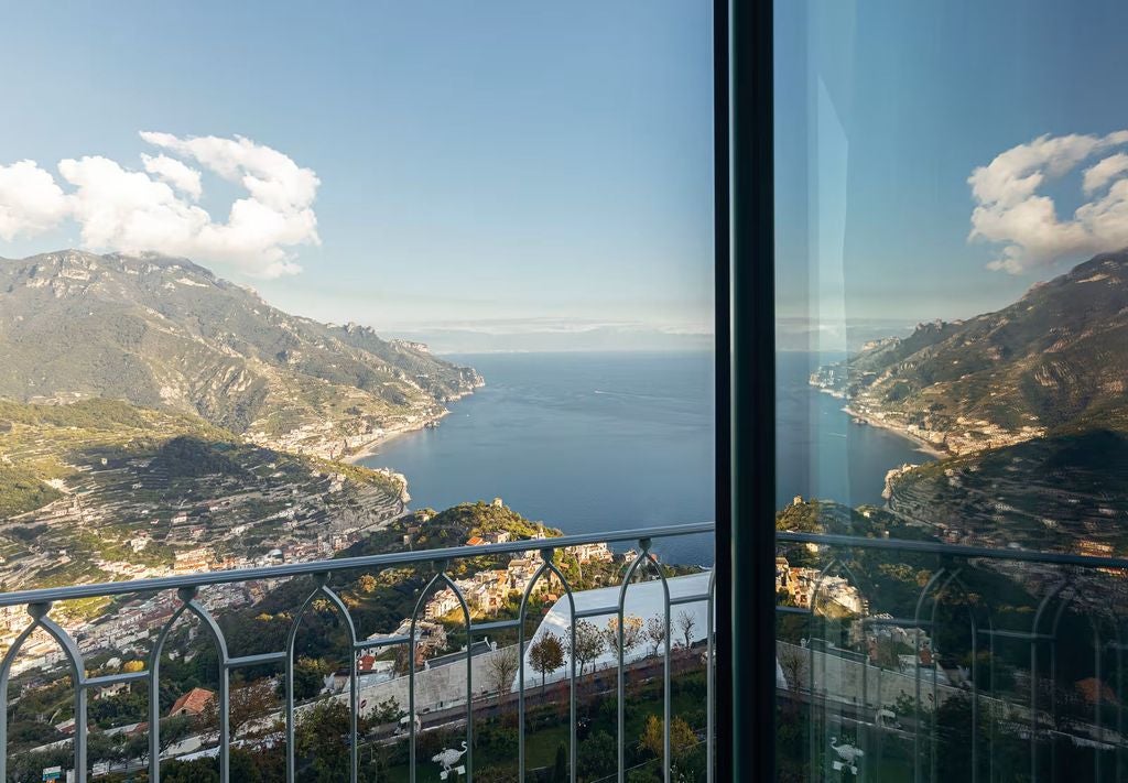 Historic Italian villa hotel with infinity pool overlooking Amalfi Coast cliffs, Mediterranean Sea and terraced gardens at sunset