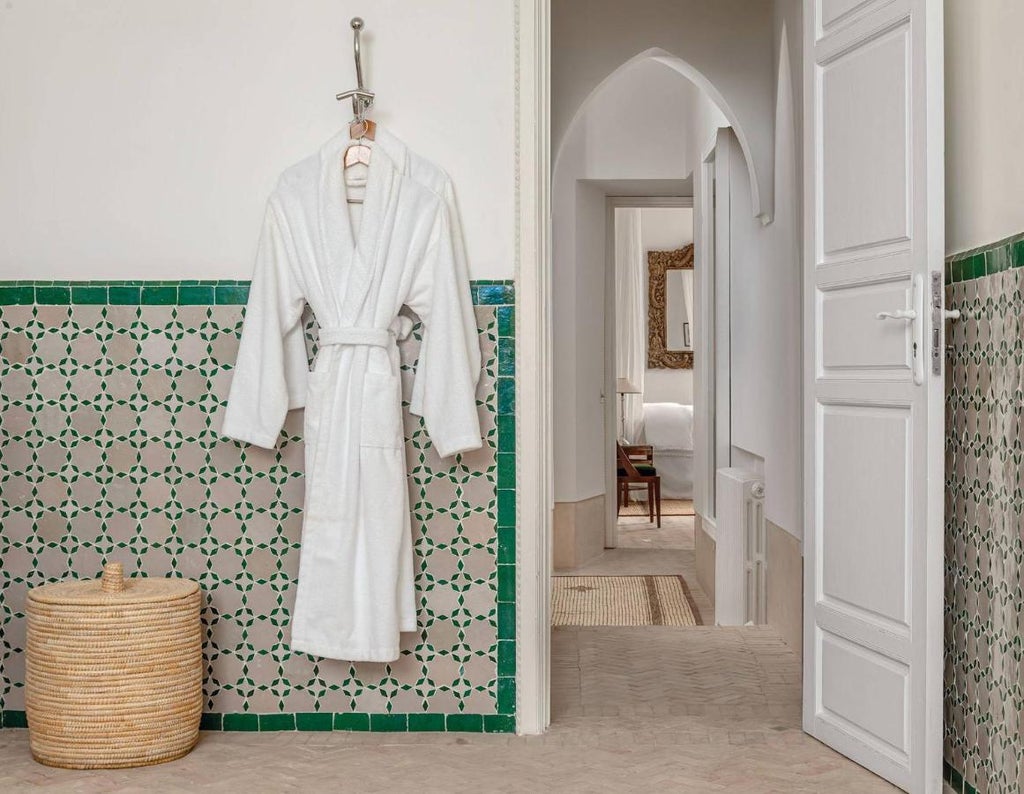 Elegant Moroccan riad courtyard with ornate archways, marble fountain, and traditional seating around lush greenery and palm trees