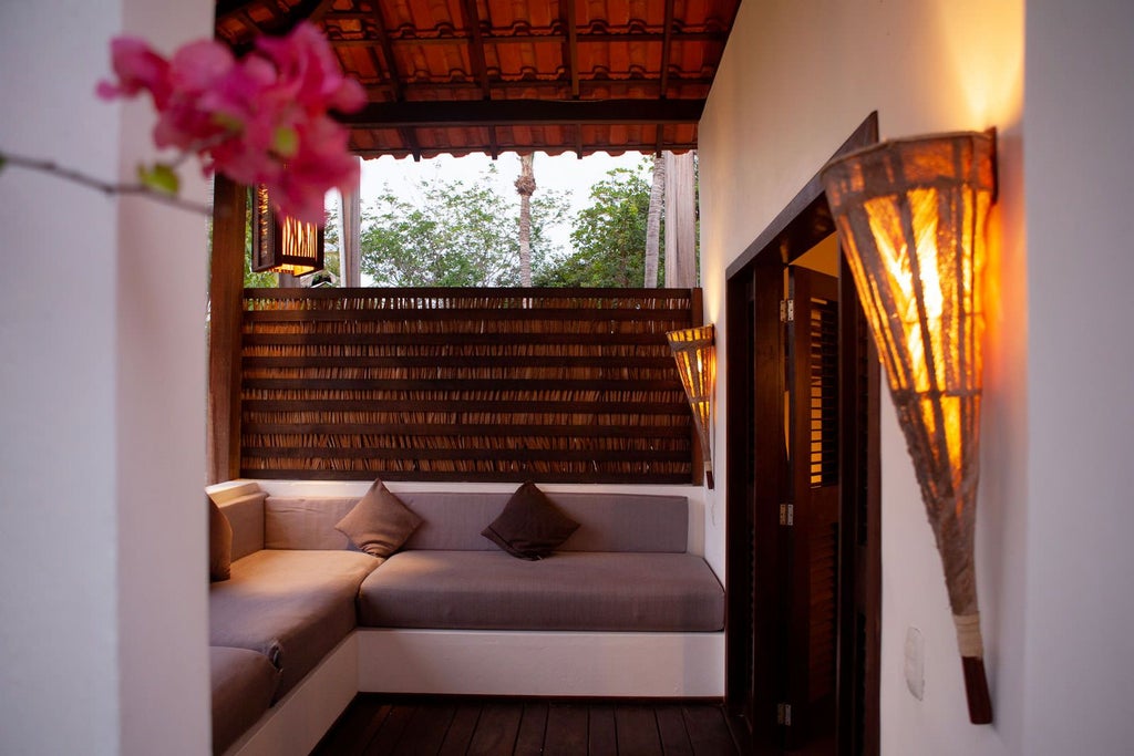 Elegant garden-view lodge room with plush white bedding, rustic wooden furniture, and large windows overlooking lush Brazilian riverside landscape at sunset