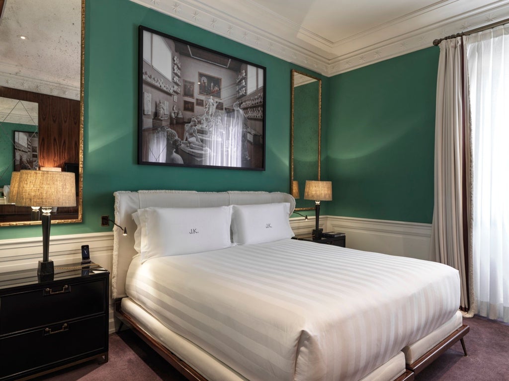 Elegant white-washed deluxe double room with plush ivory bedding, antique Italian furnishings, and soft ambient lighting at luxury boutique hotel in Roma.