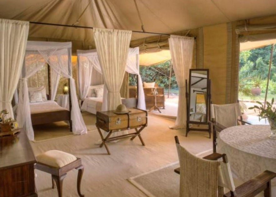 Spacious safari-style family tent with elegant colonial furnishings, four-poster beds, antique decor and expansive canvas views of Kenyan savanna