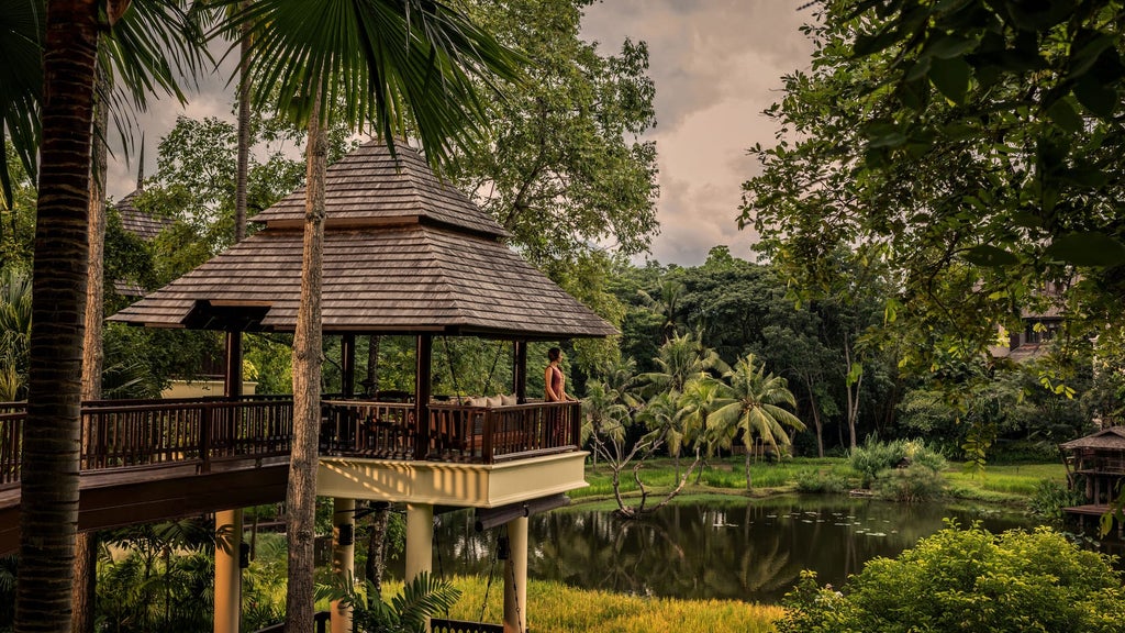 Luxury Thai villa with infinity pool overlooking lush rice terraces and mountains, surrounded by tropical gardens at sunset