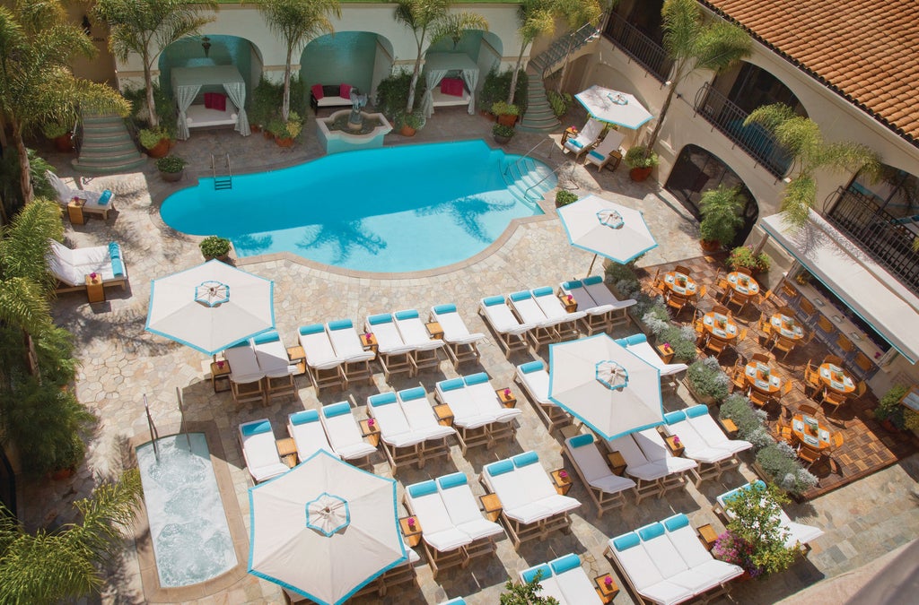 Iconic Four Seasons Beverly Wilshire hotel's grand Mediterranean Revival façade with palm trees and fountain at golden hour