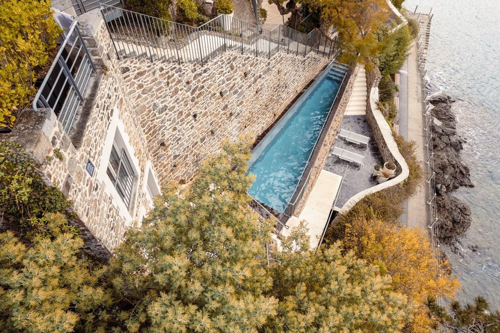 Elegant seaside boutique hotel nestled on rocky Brittany coastline, showcasing azure waters, stone architecture, and white-trimmed windows at Castelbrac Hotel & Spa.