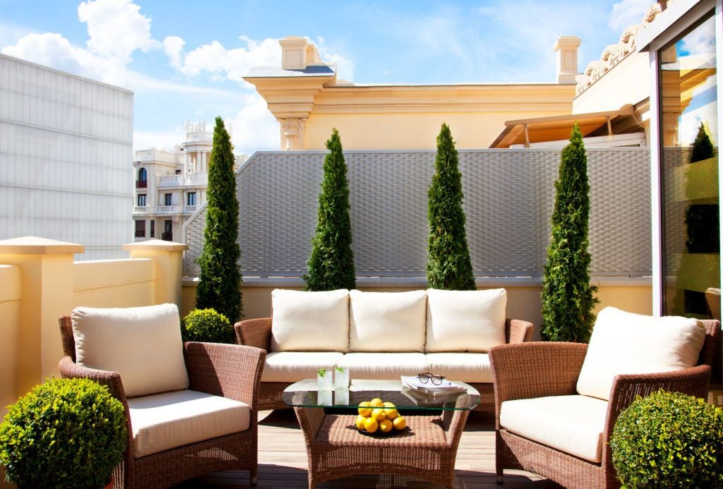 Elegant 5-star luxury hotel with cream-colored facade, ornate balconies, and classic Spanish architectural details in central Madrid's historic district