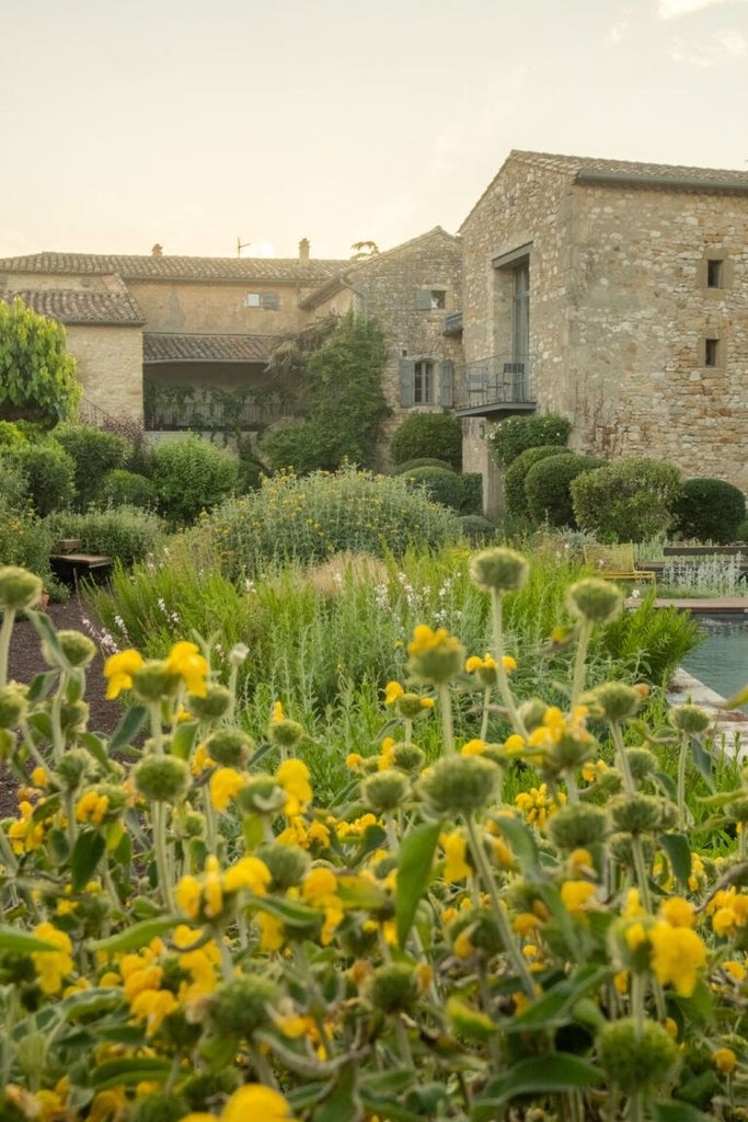 Elegant stone-walled luxury hotel with rustic terracotta roof, surrounded by lavender fields and Provençal landscape in southern France