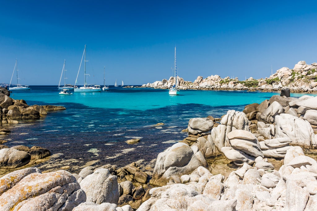 Scenic Mediterranean beach on Corsica's rugged coastline with crystal-clear turquoise waters, white sand, and dramatic mountain backdrop