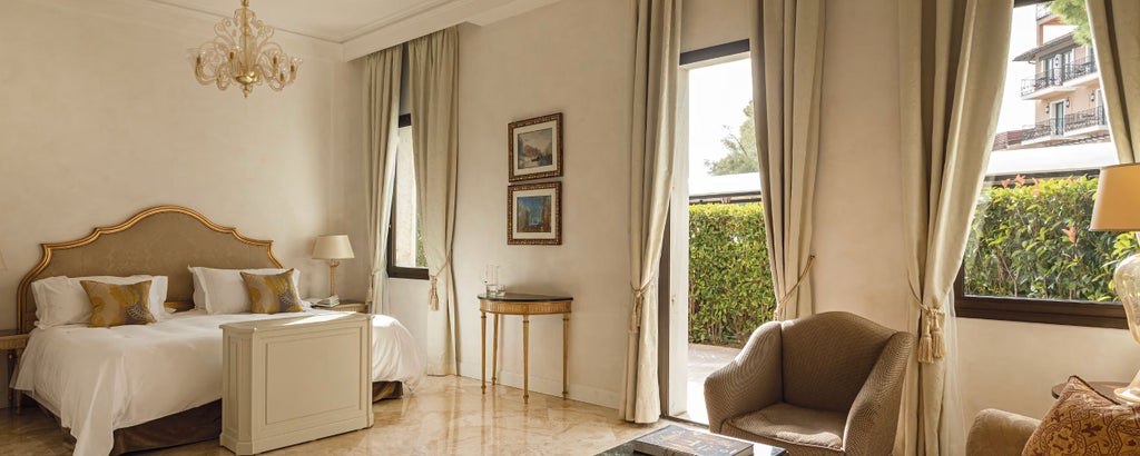 Elegant superior hotel room with French doors opening to private patio, featuring marble bathroom and Venetian-style furnishings